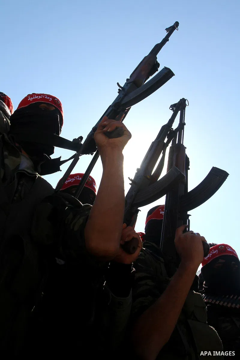 Palestinian militants hold up their weapons as they attend the funeral of three Palestinian men who were shot dead by Israeli forces, in Beit Lahia, northern Gaza Strip, on February 17, 2011. The three men were killed ov...