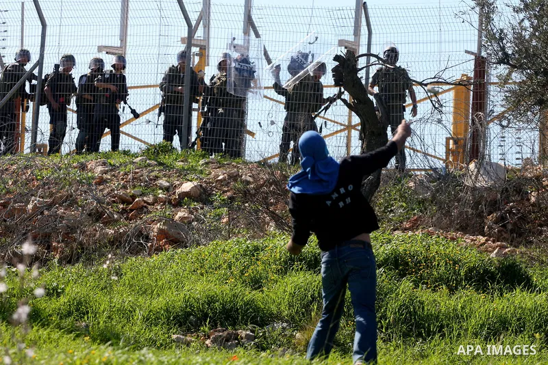 Palestinian protesters hurl stones towards Israeli soldiers during the weekly demonstration against Israel's separation barrier in the West Bank village of Bilin near Ramallah, Friday, Feb. 18, 2011. Photo by Issam Rimaw...