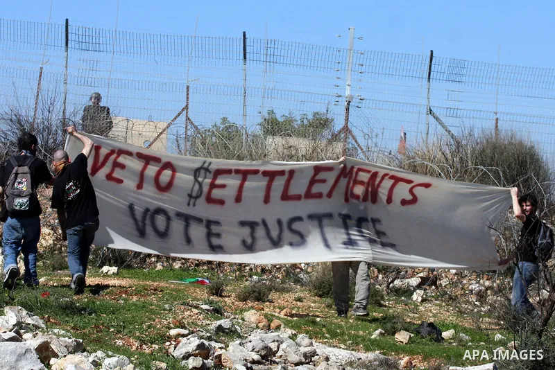 Protesters hold signs during the weekly demonstration against Israel's separation barrier in the West Bank village of Bilin near Ramallah, Friday, Feb. 18, 2011. Photo by Issam Rimawi