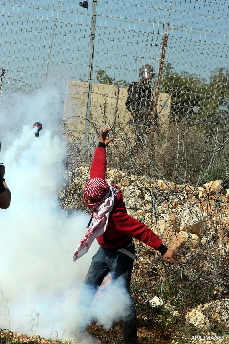 An Israeli soldier fires tear gas canisters towards protesters during the weekly demonstration against Israel's separation barrier in the West Bank village of Bilin near Ramallah, Friday, Feb. 18, 2011. Photo by Issam Ri...