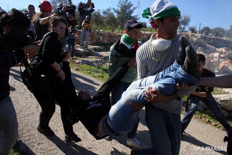 Palestinian protesters help a wounded youth during the weekly demonstration against Israel's separation barrier in the West Bank village of Bilin near Ramallah, Friday, Feb. 18, 2011. Photo by Issam Rimawi