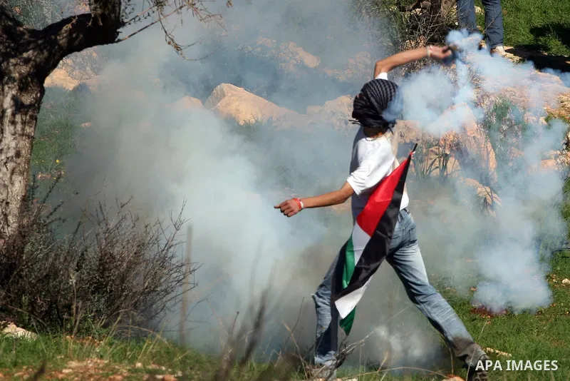 A Palestinian protester returns tear gas canister towards Israeli soldiers during the weekly demonstration against Israel's separation barrier in the West Bank village of Bilin near Ramallah, Friday, Feb. 18, 2011. Photo...