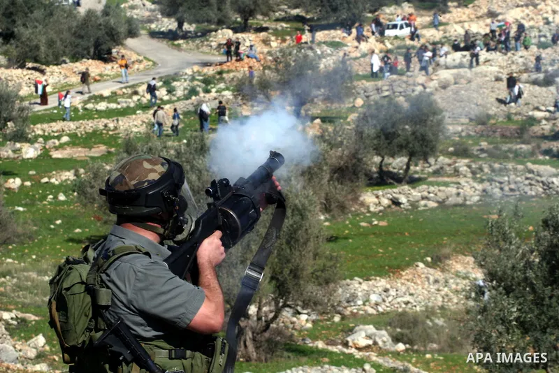 An Israeli soldier fires tear gas canisters towards protesters during the weekly demonstration against Israel's separation barrier in the West Bank village of Bilin near Ramallah, Friday, Feb. 18, 2011. Photo by Issam Ri...