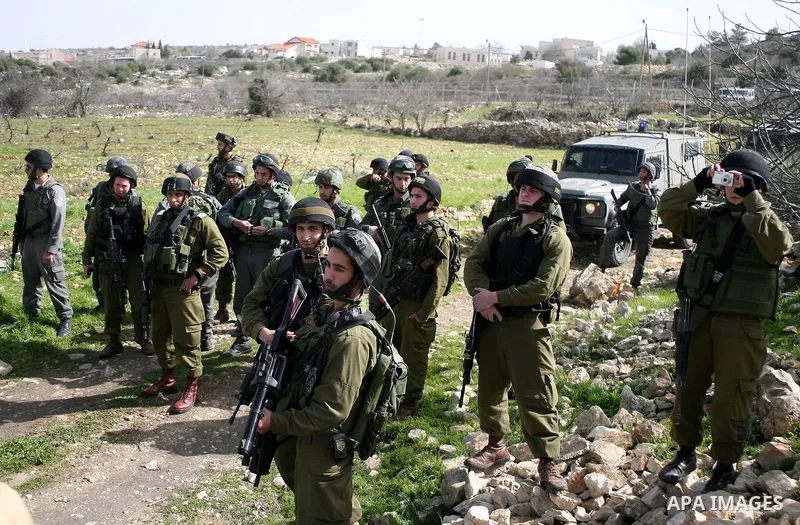 Israeli soldiers stand guard during a demonstration by Palestinian, Israeli and foreign activists against the demolishing of farm land to be used in the construction of Jewish settlements near the existing Israeli settle...