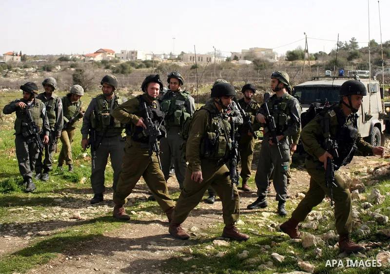 Israeli soldiers stand guard during a demonstration by Palestinian, Israeli and foreign activists against the demolishing of farm land to be used in the construction of Jewish settlements near the existing Israeli settle...