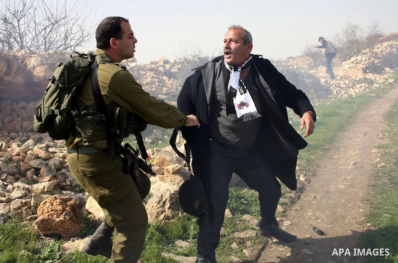 An Israeli soldier argues with a protester during a demonstration by Palestinian, Israeli and foreign activists against the demolishing of farm land to be used in the construction of Jewish settlements near the existing...