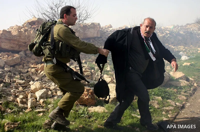 An Israeli soldier argues with a protester during a demonstration by Palestinian, Israeli and foreign activists against the demolishing of farm land to be used in the construction of Jewish settlements near the existing...