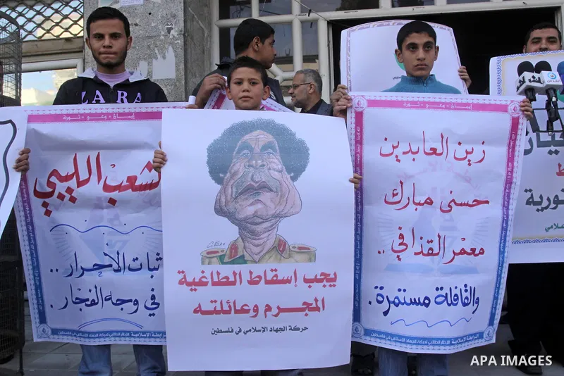 Palestinians hold up placards during a protest against Libyan leader Moamer Kadhafi in Gaza City on February 22, 2011. Gaza's Jihad Islamic rulers heaped condemnation on "the massacres" of anti-government protestors in L...
