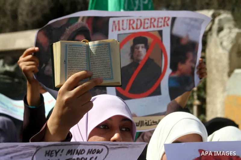Palestinian students hold up the Koran and placards during a protest against Libyan leader Moamer Kadhafi, in Gaza City on February 22, 2011. Gaza's Hamas rulers heaped condemnation on "the massacres" of anti-government...