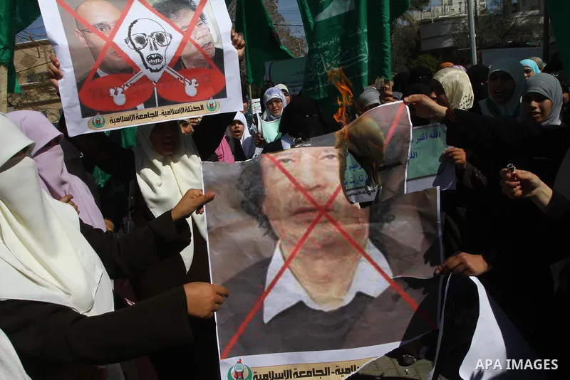 Palestinian students burn a poster of Libyan leader Moammar Gadhafi during a march in solidarity with Libya, in Gaza City, Tuesday, Feb. 22 , 2011. Gadhafi's 42-year rule is under unprecedented pressure from an uprising...