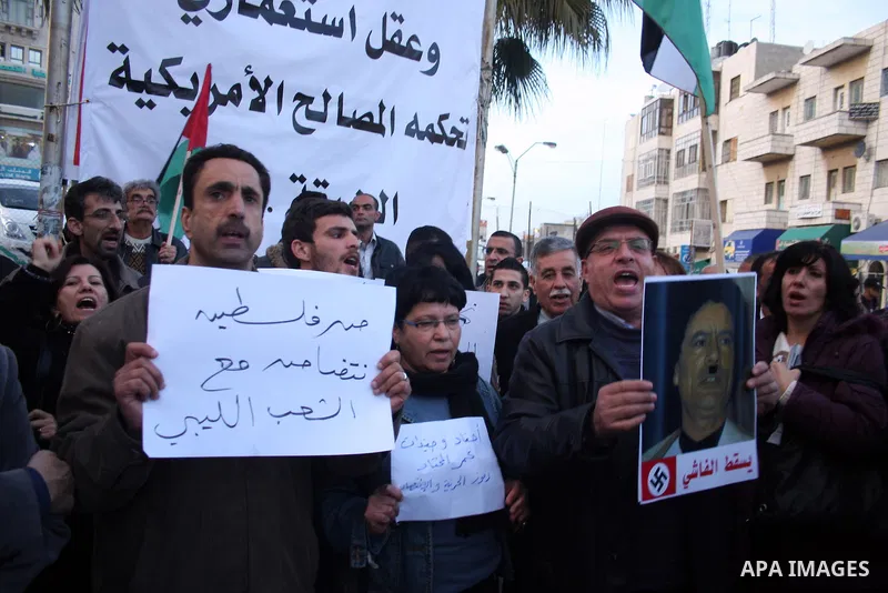 Palestinians hold up placards during a protest against Libyan leader Moamer Kadhafi,in the West Bank city of Ramallah on Feb. 22, 2011. Photo by Issam Rimawi