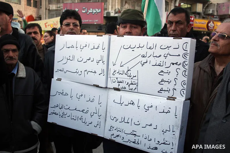 Palestinians hold up placards during a protest against Libyan leader Moamer Kadhafi,in the West Bank city of Ramallah on Feb. 22, 2011. Photo by Issam Rimawi