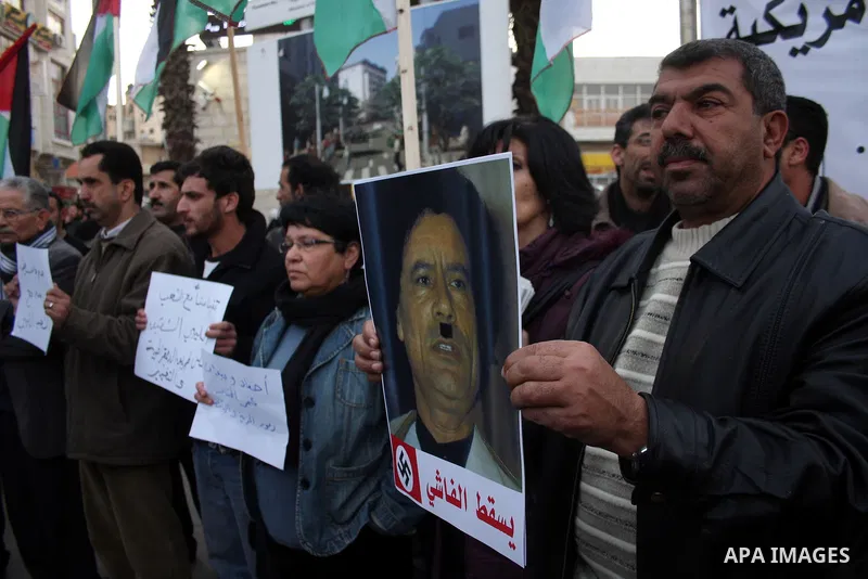 Palestinians hold up placards during a protest against Libyan leader Moamer Kadhafi,in the West Bank city of Ramallah on Feb. 22, 2011. Photo by Issam Rimawi
