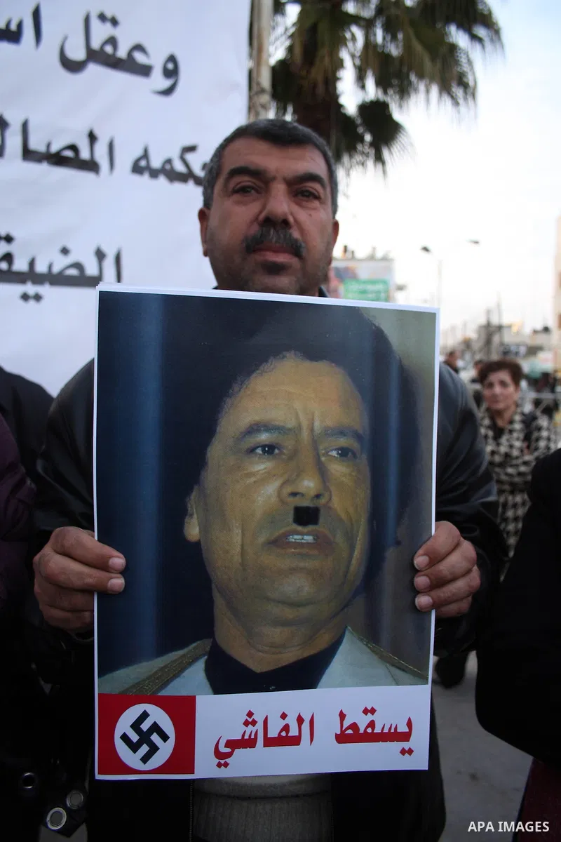 A Palestinian man holds up a placard during a protest against Libyan leader Moamer Kadhafi,in the West Bank city of Ramallah on Feb. 22, 2011. Photo by Issam Rimawi