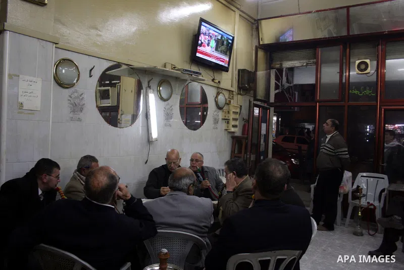Palestinians inside the coffee watching on television the speech of Libyan leader Moamer Kadhafi, in the West Bank city of Ramallah on Feb. 22, 2011. Photo by Issam Rimawi