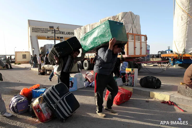 Egyptians, who have fled from Libya through the Salloum land port gate wait with their luggage,Tuesday, Feb. 22, 2011. An estimated 5,000 Egyptians have returned home from Libya by land, and about 10,000 more are waiting...