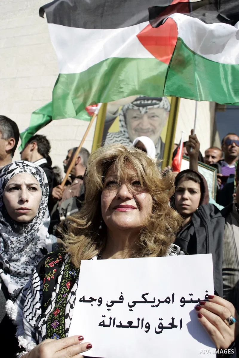 Palestinian protesters hold national flags and banners during a rally against the U.S. veto and calling for the national reconciliation in the West Bank city of Bethlehem, on Feb. 23, 2011. Photo by Najeh Hashlamoun