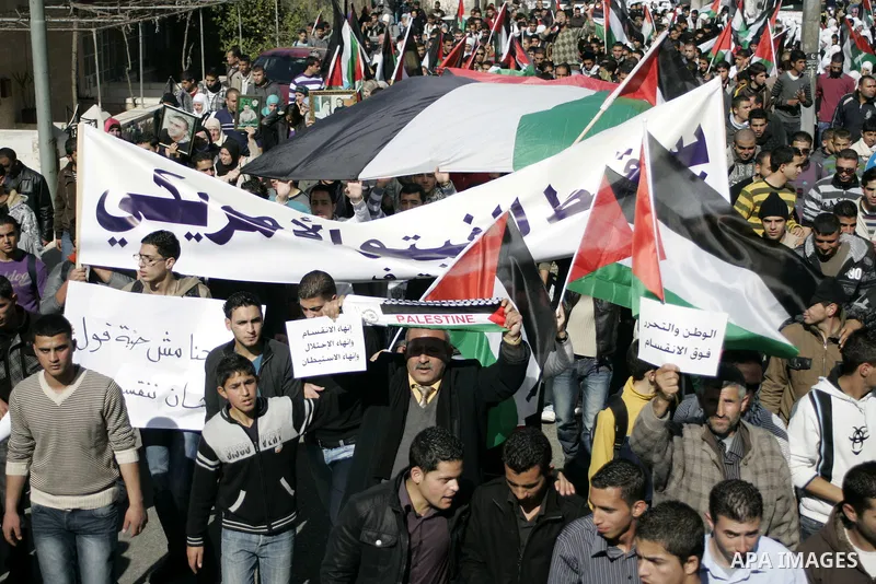 Palestinian protesters hold national flags and banners during a rally against the U.S. veto and calling for the national reconciliation in the West Bank city of Bethlehem, on Feb. 23, 2011. Photo by Najeh Hashlamoun