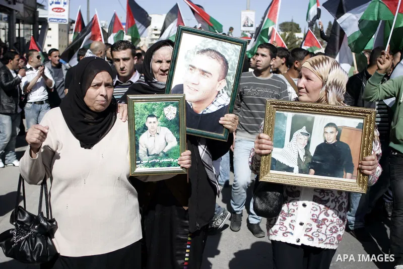 Palestinian protesters hold national flags and banners during a rally against the U.S. veto and calling for the national reconciliation in the West Bank city of Bethlehem, on Feb. 23, 2011. Photo by Najeh Hashlamoun