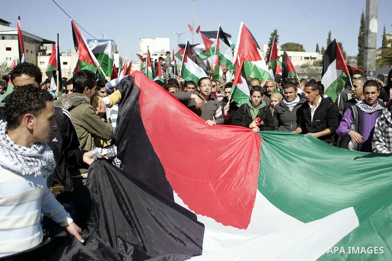 Palestinian protesters hold national flags and banners during a rally against the U.S. veto and calling for the national reconciliation in the West Bank city of Bethlehem, on Feb. 23, 2011. Photo by Najeh Hashlamoun