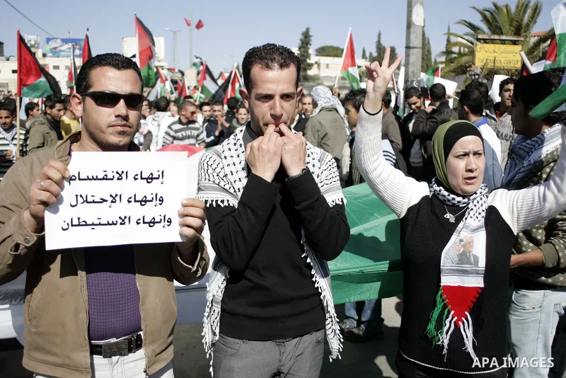 Palestinian protesters hold national flags and banners during a rally against the U.S. veto and calling for the national reconciliation in the West Bank city of Bethlehem, on Feb. 23, 2011. Photo by Najeh Hashlamoun