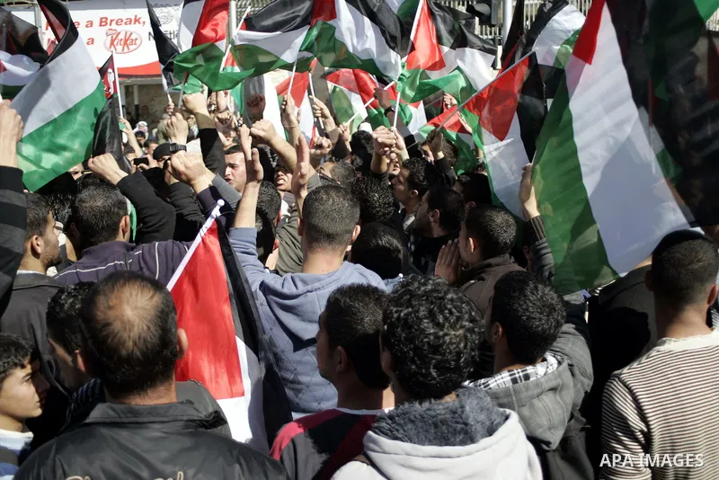 Palestinian protesters hold national flags and banners during a rally against the U.S. veto and calling for the national reconciliation in the West Bank city of Bethlehem, on Feb. 23, 2011. Photo by Najeh Hashlamoun