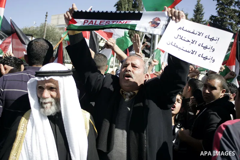 Palestinian protesters hold national flags and banners during a rally against the U.S. veto and calling for the national reconciliation in the West Bank city of Bethlehem, on Feb. 23, 2011. Photo by Najeh Hashlamoun
