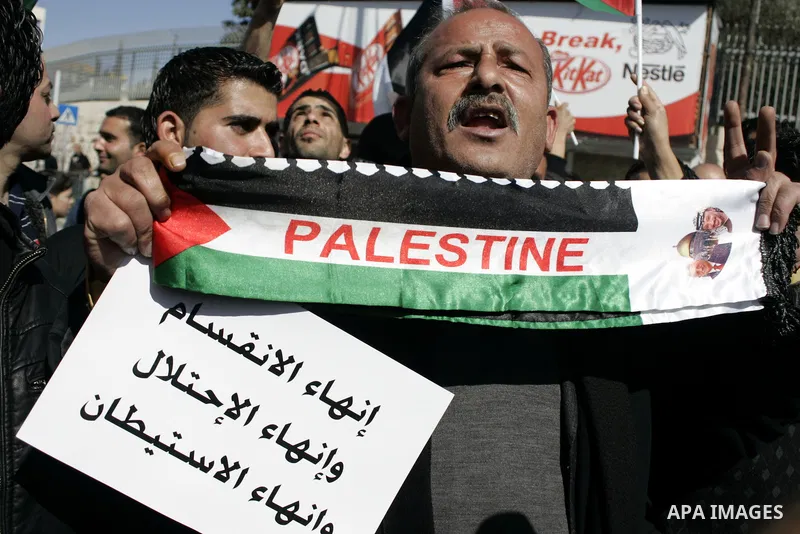 Palestinian protesters hold national flags and banners during a rally against the U.S. veto and calling for the national reconciliation in the West Bank city of Bethlehem, on Feb. 23, 2011. Photo by Najeh Hashlamoun