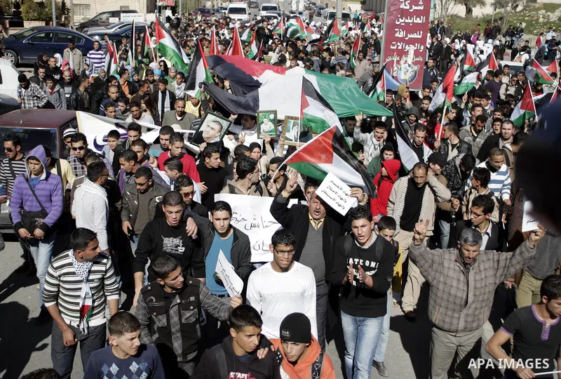 Palestinian protesters hold national flags and banners during a rally against the U.S. veto and calling for the national reconciliation in the West Bank city of Bethlehem, on Feb. 23, 2011. Photo by Najeh Hashlamoun