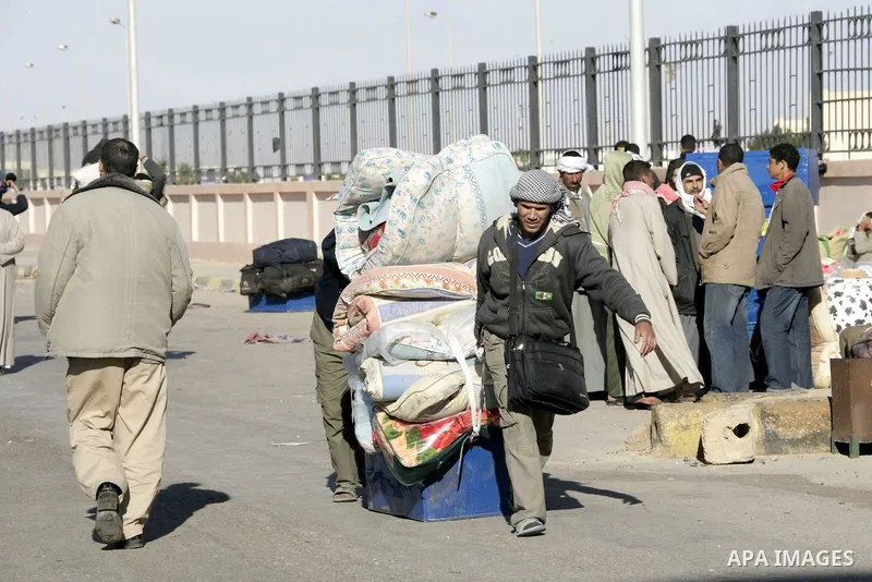Egyptians, who have fled from Libya through the Salloum land port gate wait with their luggage,Wednesday, Feb. 23, 2011. An estimated 5,000 Egyptians have returned home from Libya by land, and about 10,000 more are waiti...