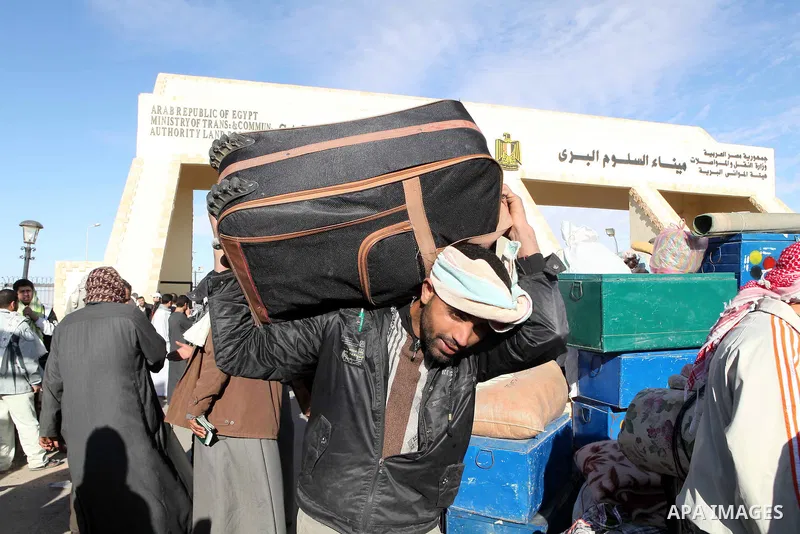 Egyptians, who have fled from Libya through the Salloum land port gate wait with their luggage,Wednesday, Feb. 23, 2011. An estimated 5,000 Egyptians have returned home from Libya by land, and about 10,000 more are waiti...