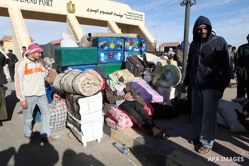 Egyptians, who have fled from Libya through the Salloum land port gate wait with their luggage,Wednesday, Feb. 23, 2011. An estimated 5,000 Egyptians have returned home from Libya by land, and about 10,000 more are waiti...