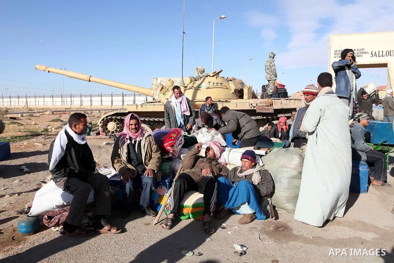 Egyptians, who have fled from Libya through the Salloum land port gate wait with their luggage,Wednesday, Feb. 23, 2011. An estimated 5,000 Egyptians have returned home from Libya by land, and about 10,000 more are waiti...