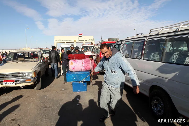Egyptians, who have fled from Libya through the Salloum land port gate wait with their luggage,Wednesday, Feb. 23, 2011. An estimated 5,000 Egyptians have returned home from Libya by land, and about 10,000 more are waiti...