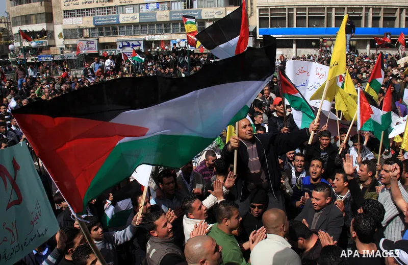 Palestinian protesters hold national flags and banners during a rally against the U.S. veto and calling for the national reconciliation in the West Bank city of Nablus, Thursday, Feb. 24, 2011. Photo by Wagdi Eshtayah