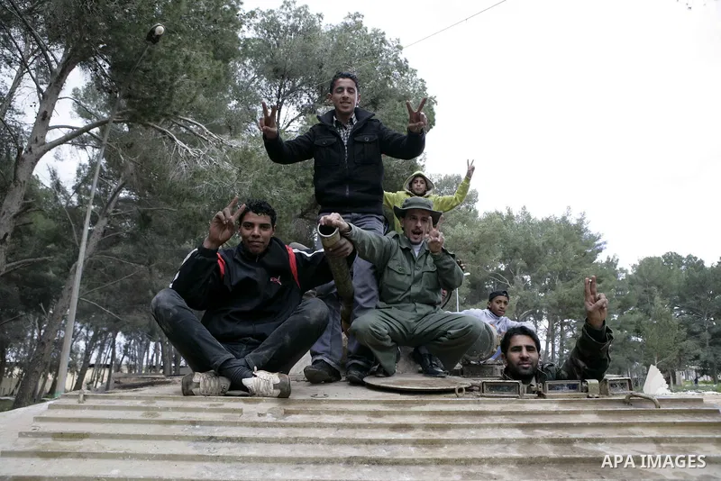 Anti-government protesters make victory signs as they stand on an army tank near a square where people are protesting in ALbedi city, Libya, February 24, 2011. Thousands of Libyans celebrated the liberation of the easter...