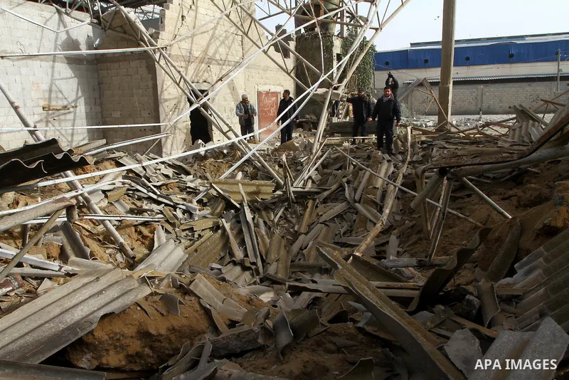 Palestinians walk across a damaged warehouse following an Israeli air strike in Nuseirat refugee camp, central Gaza Strip, Thursday, Feb. 24 , 2011. Overnight, Israeli aircraft carried out air strikes against targets in...