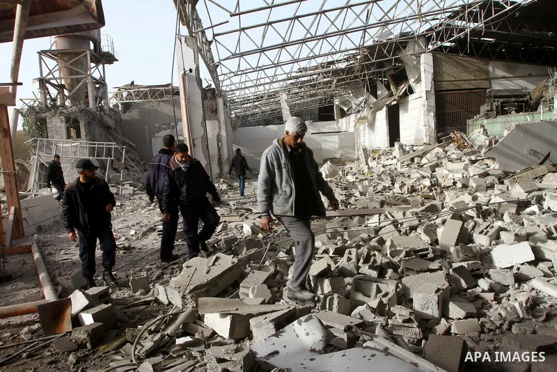 Palestinians walk across a damaged warehouse following an Israeli air strike in Nuseirat refugee camp, central Gaza Strip, Thursday, Feb. 24 , 2011. Overnight, Israeli aircraft carried out air strikes against targets in...