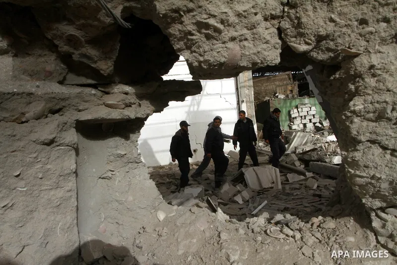 Palestinians walk across a damaged warehouse following an Israeli air strike in Nuseirat refugee camp, central Gaza Strip, Thursday, Feb. 24 , 2011. Overnight, Israeli aircraft carried out air strikes against targets in...
