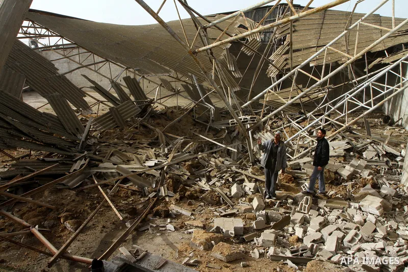Palestinians walk across a damaged warehouse following an Israeli air strike in Nuseirat refugee camp, central Gaza Strip, Thursday, Feb. 24 , 2011. Overnight, Israeli aircraft carried out air strikes against targets in...
