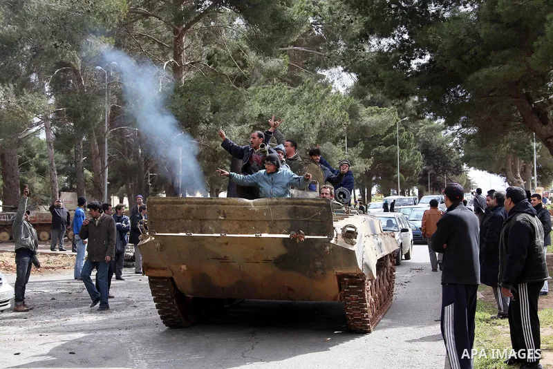 Anti-government protesters make victory signs as they stand on an army tank near a square where people are protesting in ALbedi city, Libya, February 24, 2011. Thousands of Libyans celebrated the liberation of the easter...