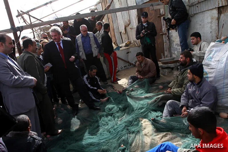 Luxembourg's Foreign Minister Jean Asselborn, centre, listens to explanation from UNRWA official upon his arrival to the Gaza fishermen port in Gaza City, Friday, Feb. 25, 2011. Asselborn is on an official visit to Gaza....