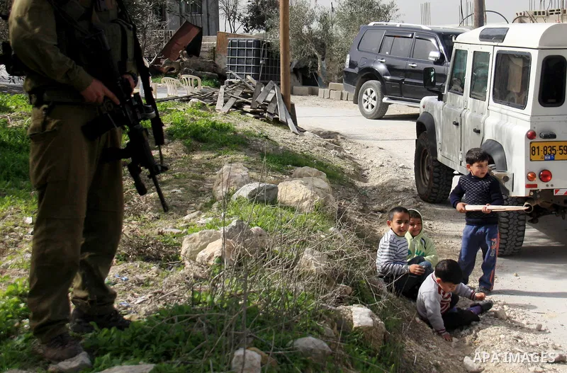 An Israeli soldier next to boy in the village of Jeet the West bank city of Qalqilya, Friday,25, 2011. Palestinians and the Israeli military said Friday Jewish settlers vandalized in a Palestinian village in the West Ban...