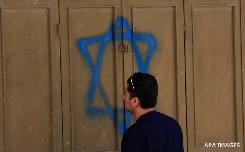 An Israeli next to the Star of david in the village of Jeet the West bank city of Qalqilya, Friday,25, 2011. Palestinians and the Israeli military said Friday Jewish settlers vandalized in a Palestinian village in the We...