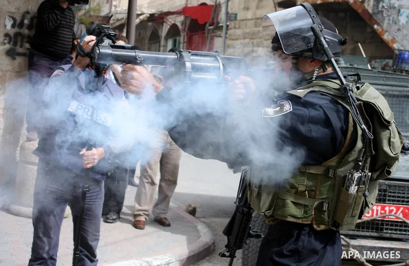 Israeli police officer fires tear gas canisters towards Palestinian, Israeli and foreign activists during a protest against the continued closure of Shuhada street to Palestinians, in the West Bank city of Hebron 25 Febr...
