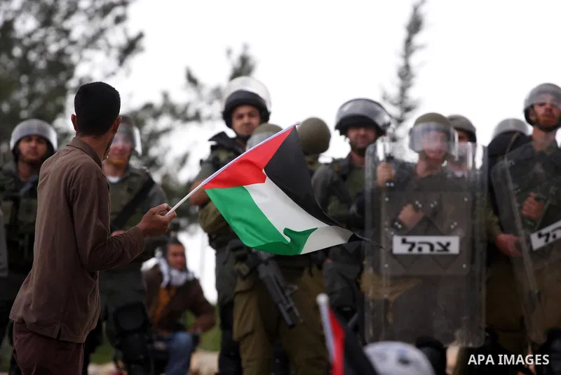 Israeli soldiers take position as Palestinians hold national flag during a protest against the controversial Israeli barrier in the West Bank village of Bilin near Ramallah, Feb. 25, 2011. Photo by Issam Rimawi