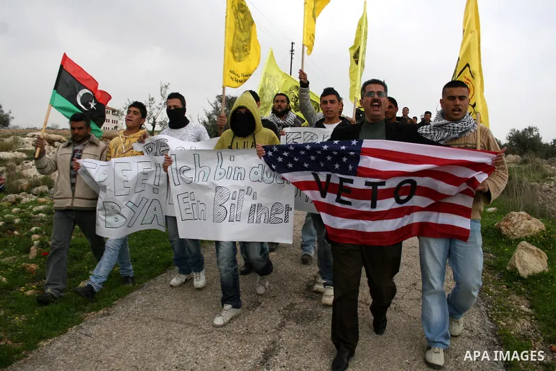Palestinian youths hold American flag during a protest against the controversial Israeli barrier in the West Bank village of Bilin near Ramallah, Feb. 25, 2011. Photo by Issam Rimawi
