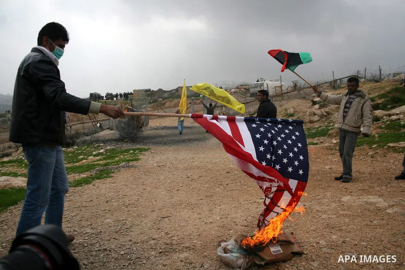 Palestinian youths burn American flag during a protest against the controversial Israeli barrier in the West Bank village of Bilin near Ramallah, Feb. 25, 2011. Photo by Issam Rimawi