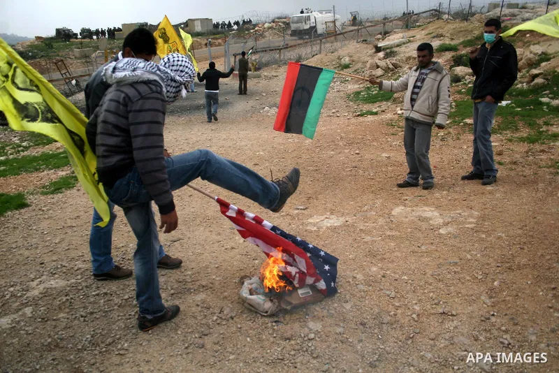 Palestinian youths burn American flag during a protest against the controversial Israeli barrier in the West Bank village of Bilin near Ramallah, Feb. 25, 2011. Photo by Issam Rimawi