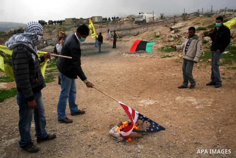 Palestinian youths burn American flag during a protest against the controversial Israeli barrier in the West Bank village of Bilin near Ramallah, Feb. 25, 2011. Photo by Issam Rimawi